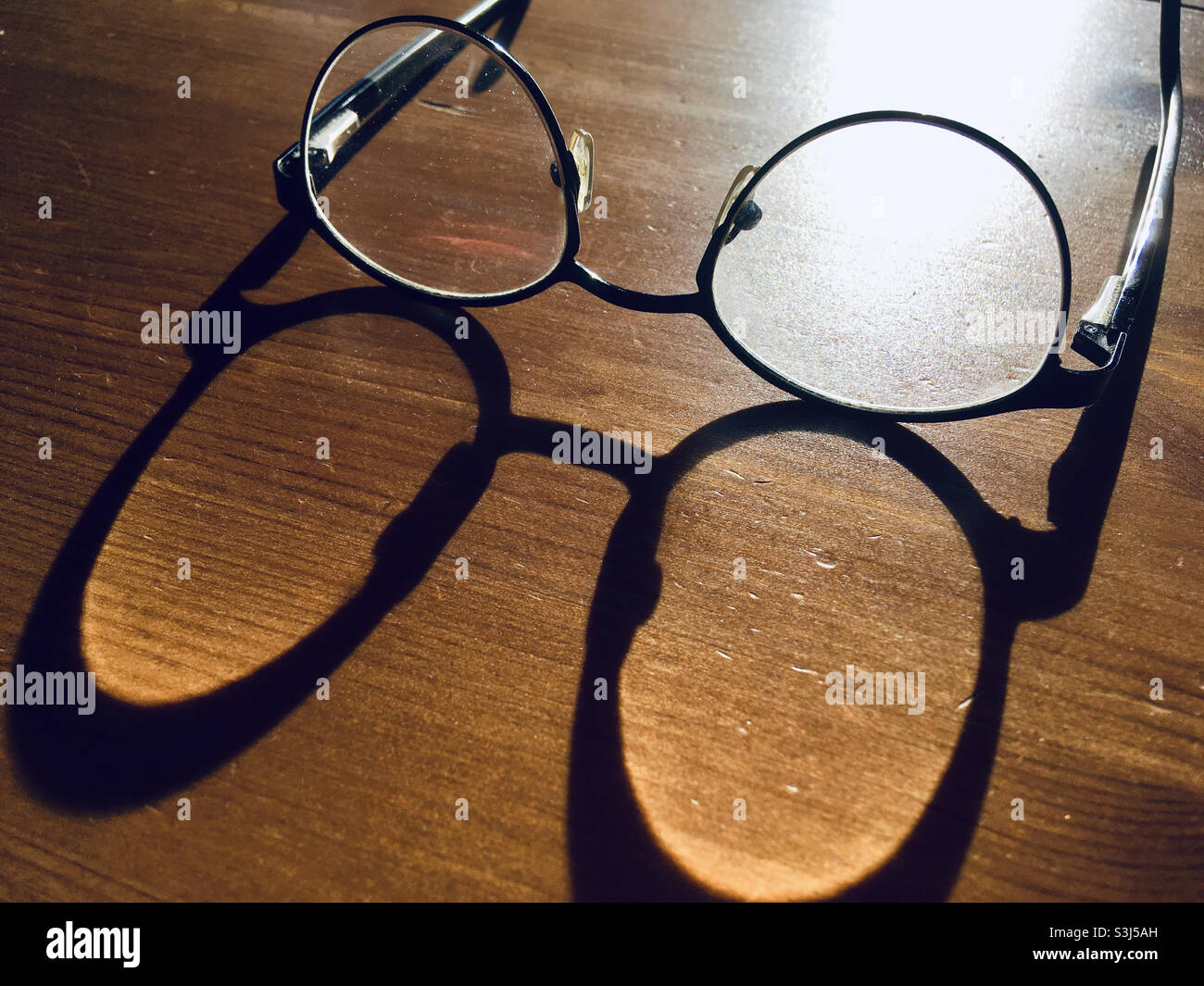 Pair of glasses on table with long shadow - Smartphone Captured Stock Image
