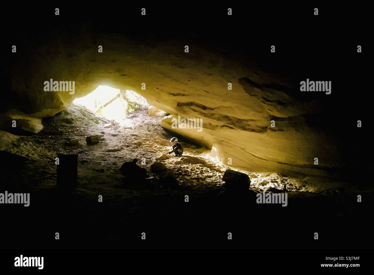 Ferenc-barlang (cave) in sandstone hill with child squatting, Dudlesz-erdo, Hungary Stock Photo