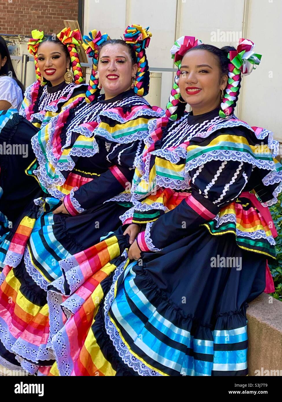 Three smiling women dancers wearing colorful traditional Mexican dresses Stock Photo