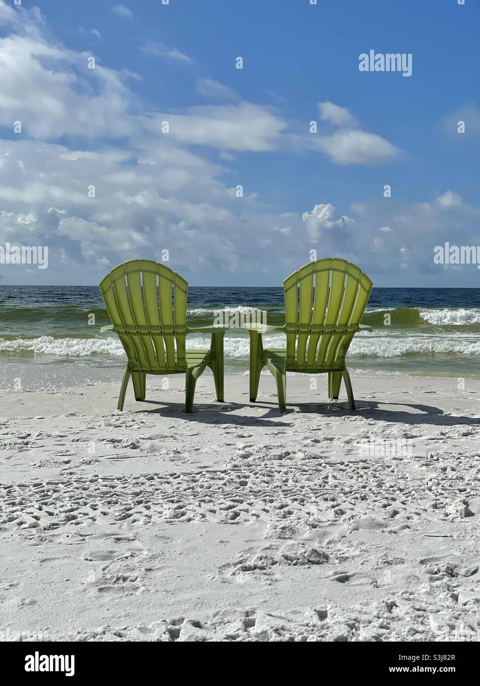 Two green outdoor chairs on Florida white sand beach facing the emerald water of the Gulf of Mexico - Smartphone Captured Stock Image