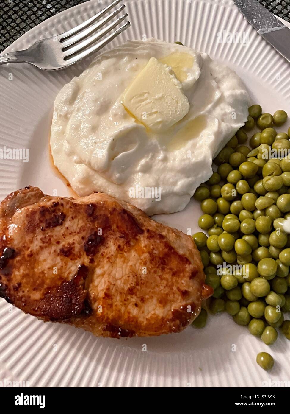 Close up of a hearty home cooked meal of pork cutlet, mashed potatoes and canned peas, 2021, united states Stock Photo
