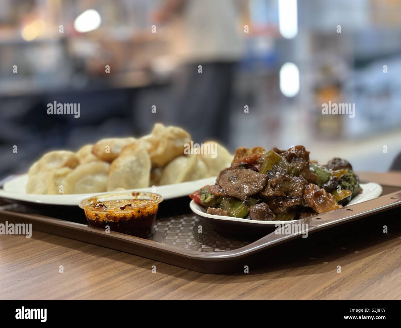 Plates of pan fried dumplings and chili and sesame seed sauce and stir fry beef and black beans Stock Photo