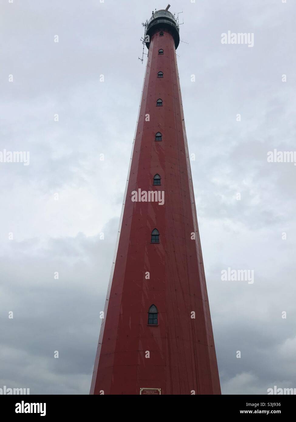 Red Lighthouse in Den Helder, Netherlands in front of a cloudy sky on a rainy day - Smartphone Captured Stock Image