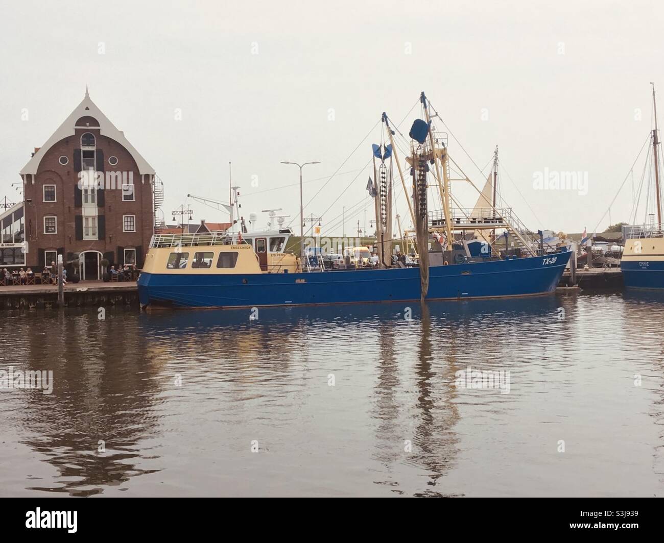 A blue fishing boat lies in the harbor oudeschild of the Dutch North Sea island texel - Smartphone Captured Stock Image