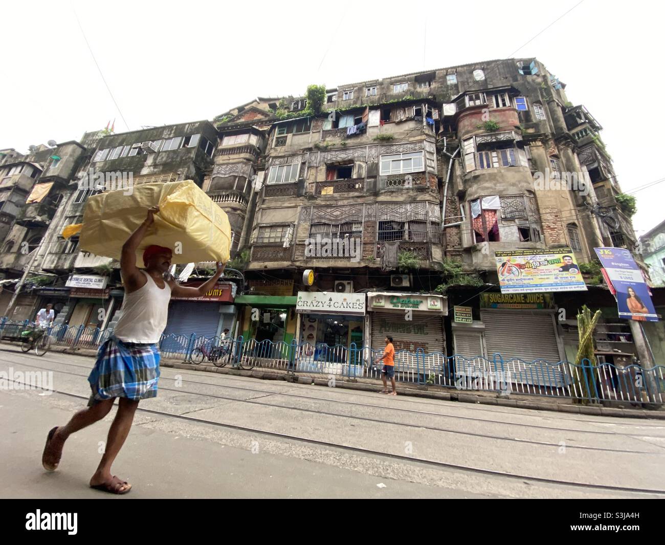 A working man carrying load upon his head on the street of old city Kolkata - Smartphone Captured Stock Image