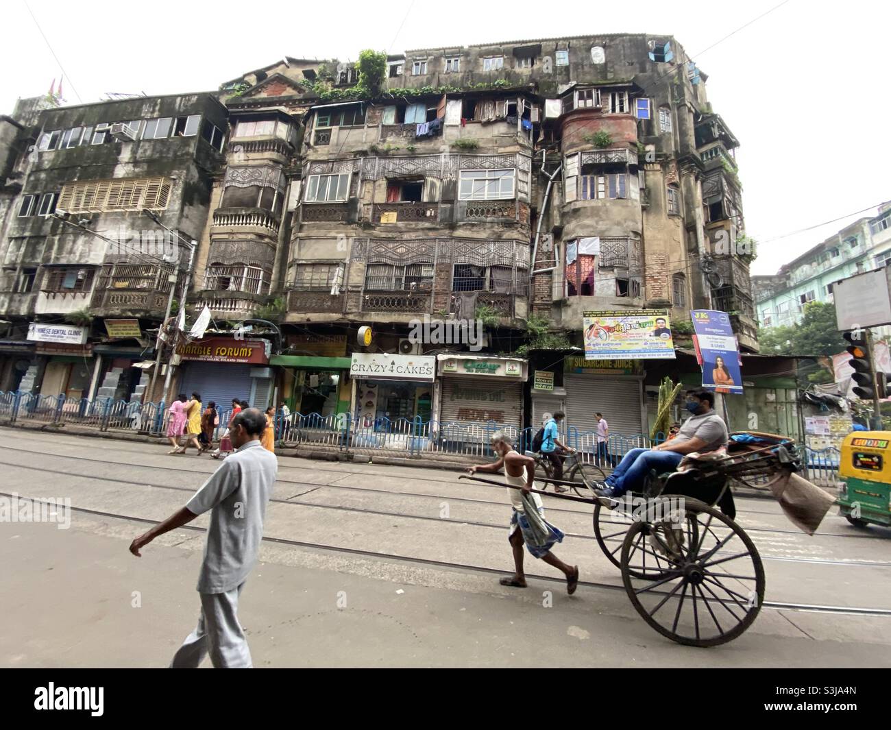 An Indian man is riding on a hand pulled rickshaw in the street of Kolkata - Smartphone Captured Stock Image