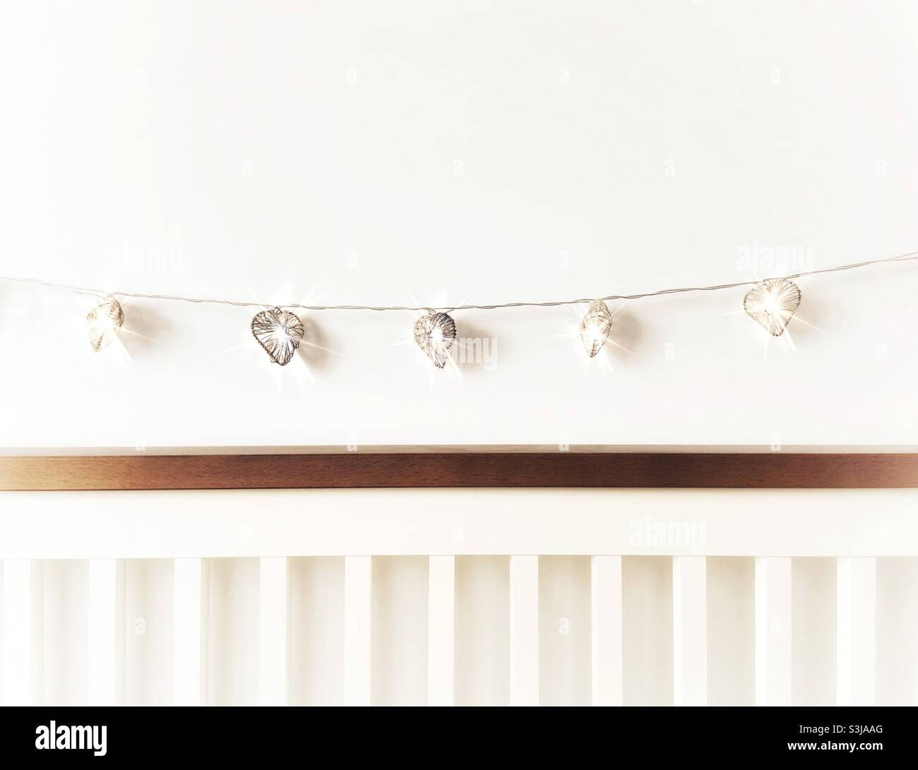 Heart shaped fairy lights strung above bed headboard Stock Photo