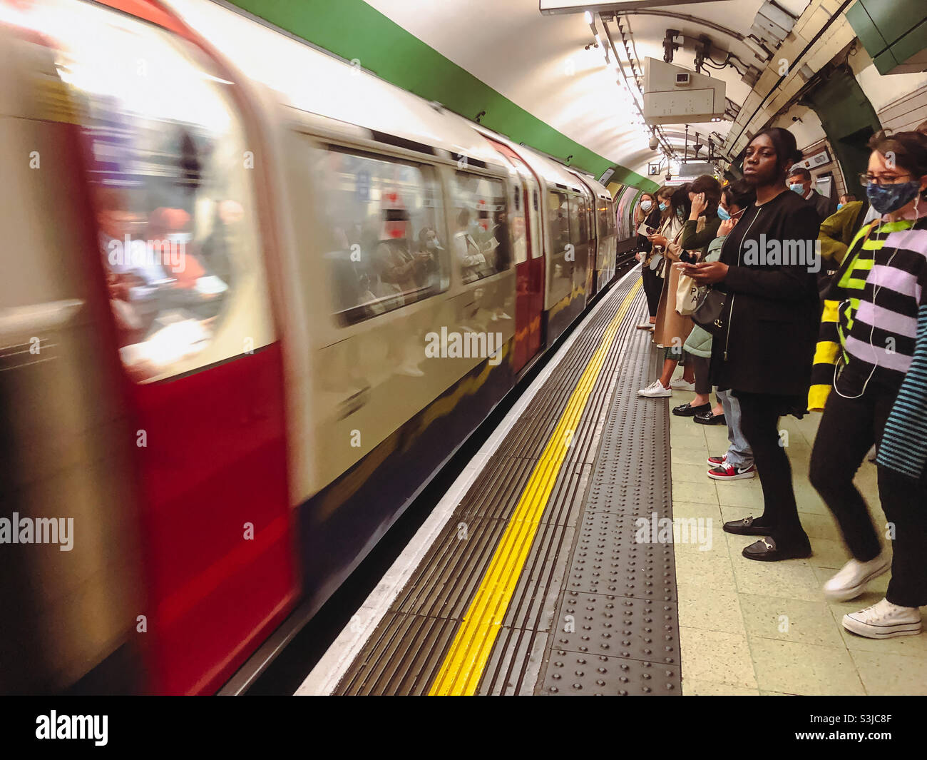 Passengers wait on the platform at Paddington London Underground Station as a train arrives at the platform. - Smartphone Captured Stock Image