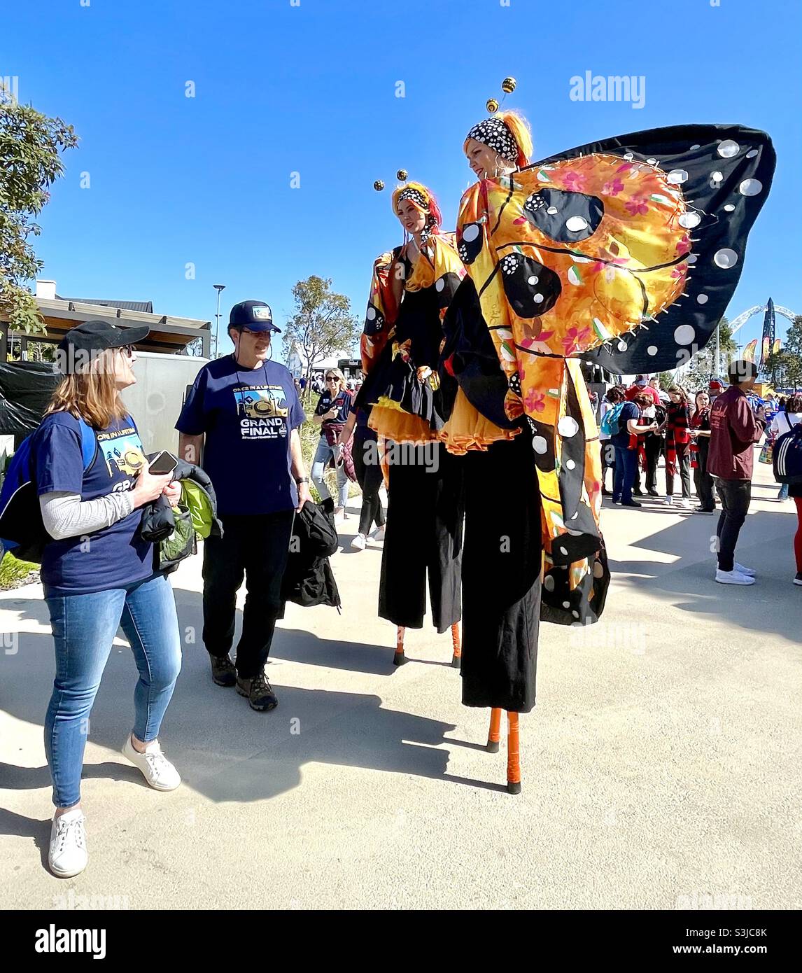 2021 AFL Grand Final at Optus Stadium, pregame crowd outside spectators near two women in butterfly costumes on stilts, Perth Western Australia. Stock Photo