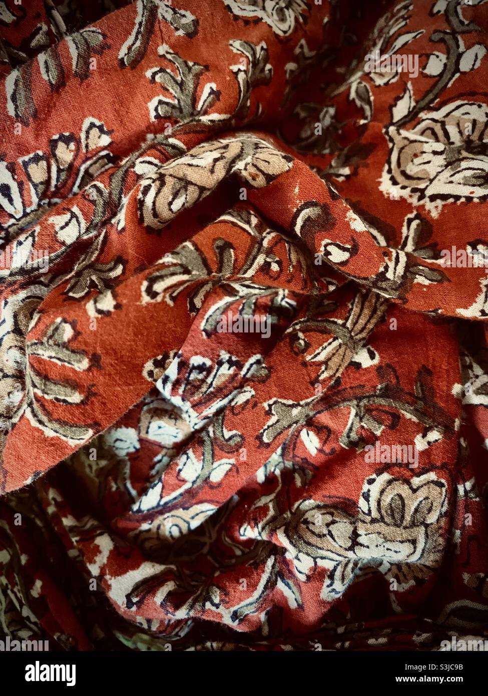 close up image of a crumpled piece of orange material with sketched flower and leaf motifs - Smartphone Captured Stock Image