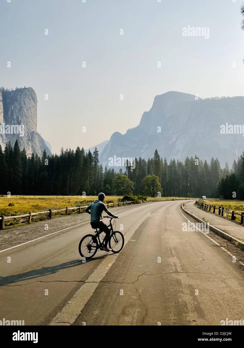 A male rides a bike in the lower Yosemite Valley with beautiful views of Half Dome. Yosemite National Park, California USA. - Smartphone Captured Stock Image