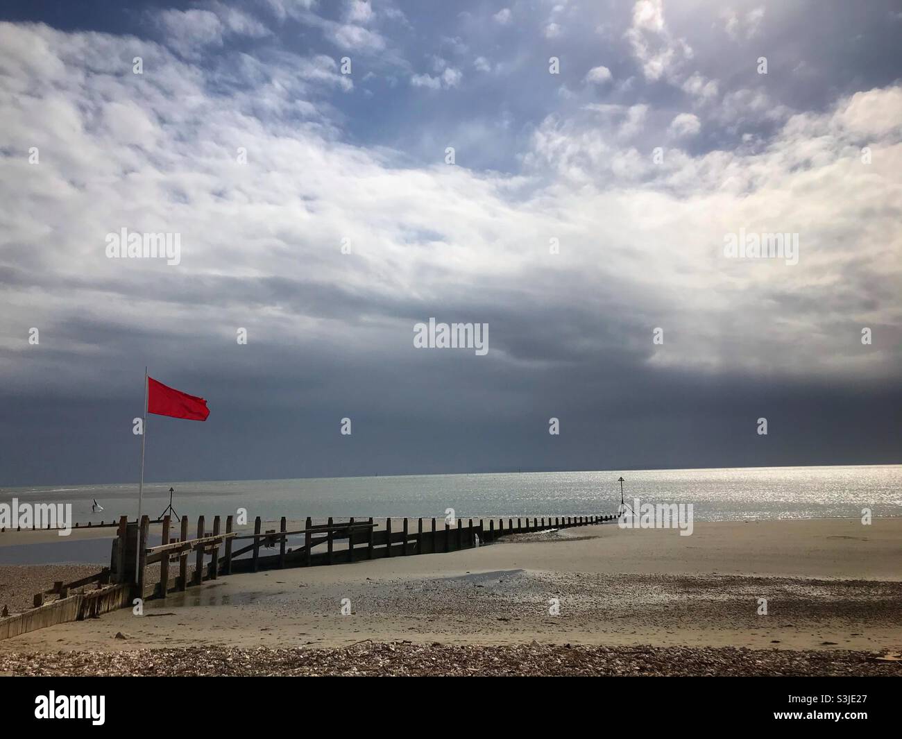 Red flag on the beach at West Wittering West Sussex UK - Smartphone Captured Stock Image
