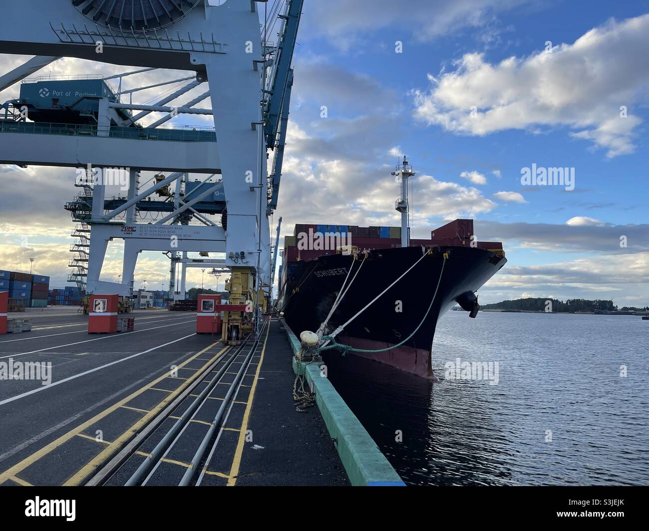 Container vessel moored alongside the pier of the terminal with gantry