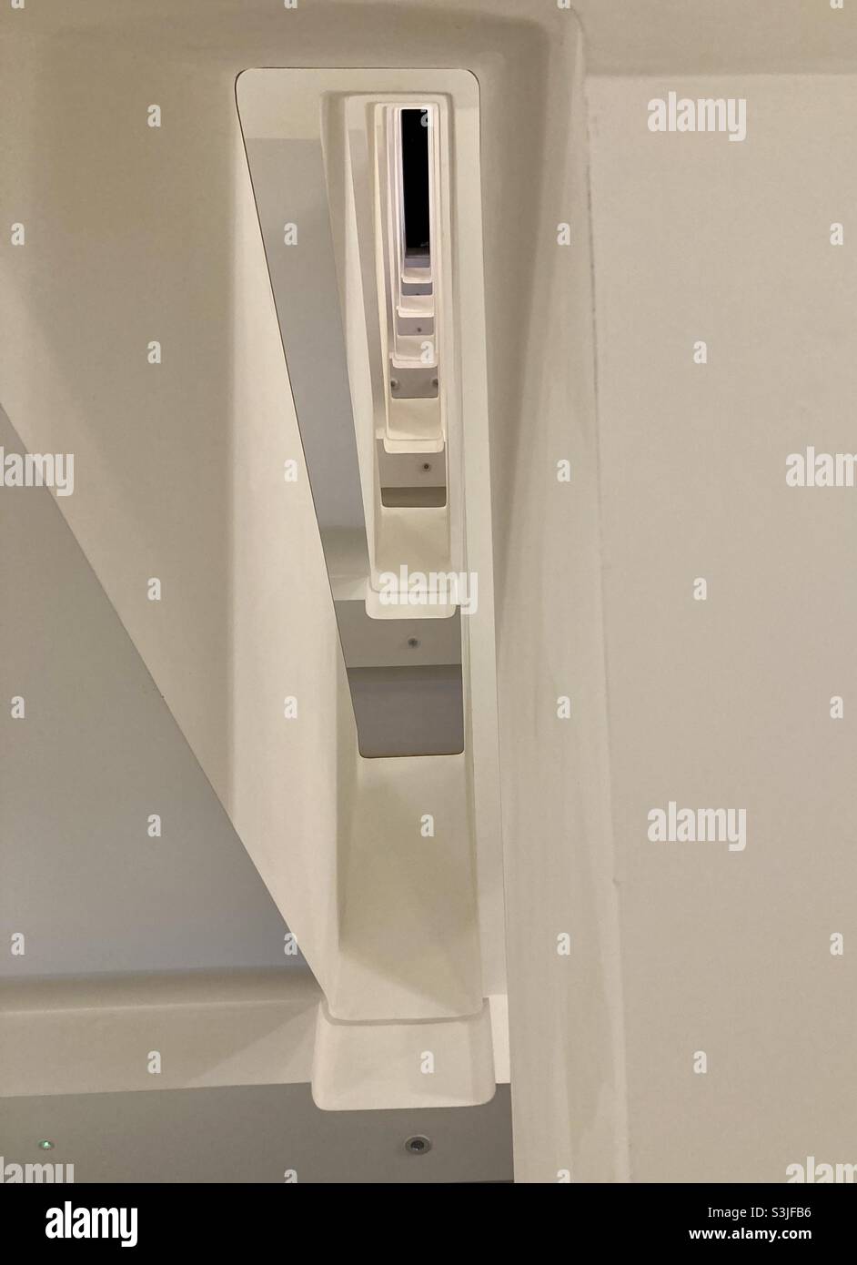 Looking up through the gap in a Modernist style architectural stairwell. Looking through the void between the concrete spiral staircase. - Smartphone Captured Stock Image