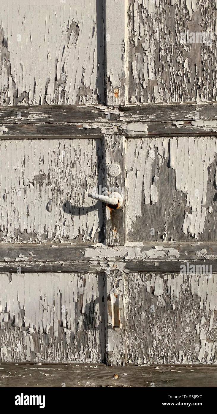 Old garage door with cracked and peeling white paint. Stock Photo