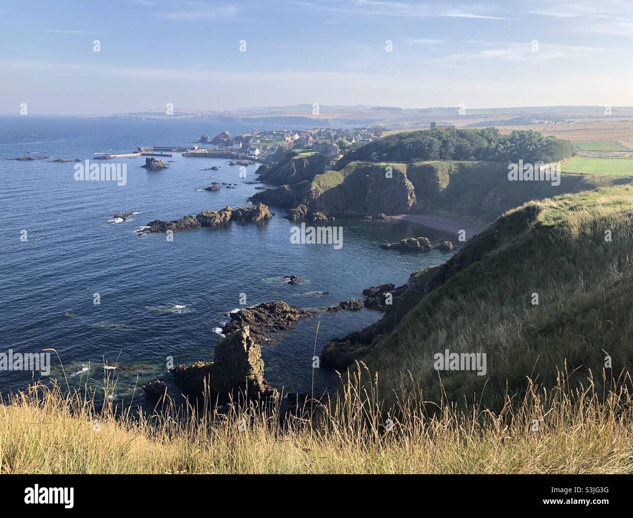 View of St Abb’s fishing coastal village and Rocky headland from St Abb’s Head nature reserve coast path Stock Photo