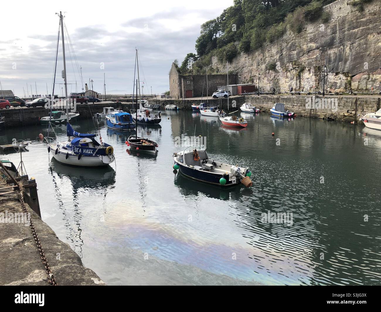 Boats and oil spill in pretty historic harbour, Dysart, Fife Stock Photo