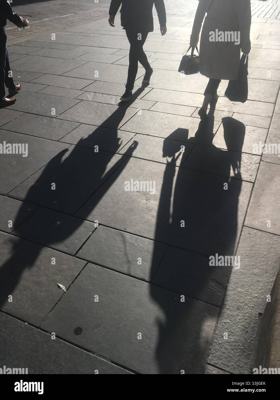 Silhouettes on the pavement of people shopping or commuting in the city - Smartphone Captured Stock Image