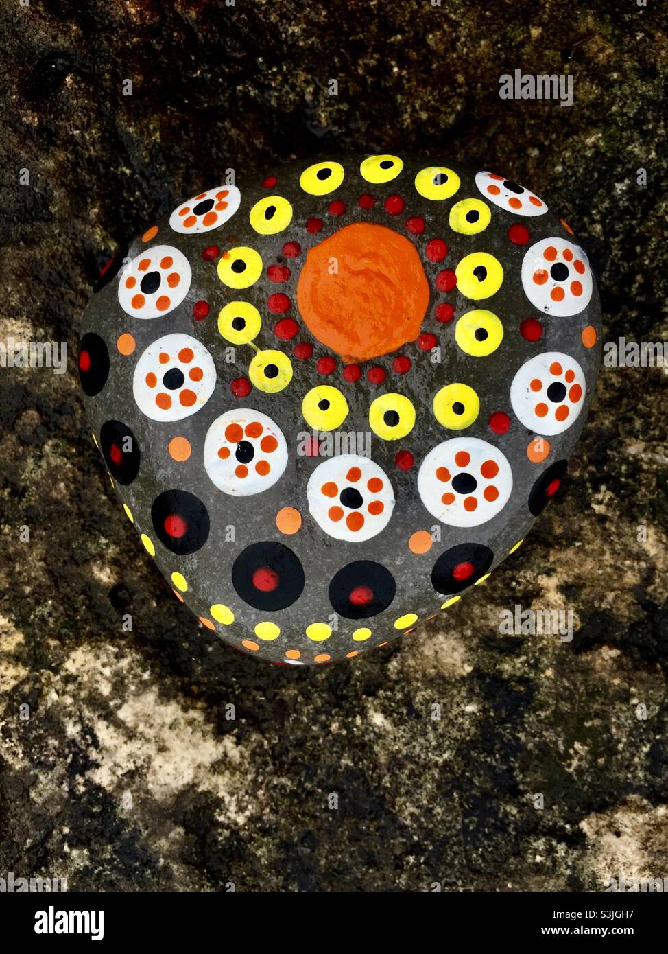 A galaxy. The sun and stars painted on a stone, an earthbound artist’s impression in circles and dots in many colours, Ontario, Canada. Celestial bodies, big and small. Freehand Art, not science. Stock Photo