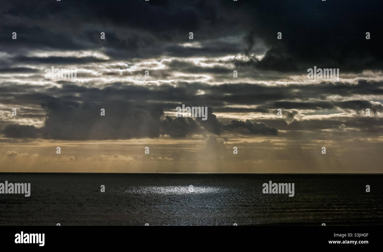 Sun through storm clouds over the sea hi-res stock photography and ...
