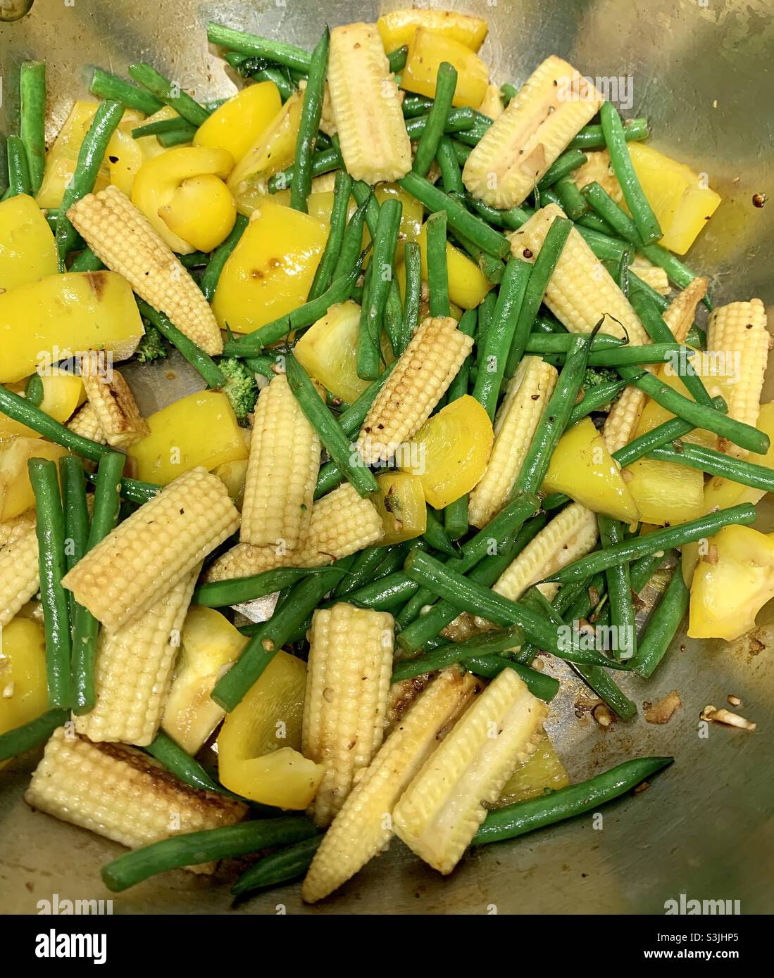 Baby corn yellow peppers and green beans frying in a wok Stock Photo