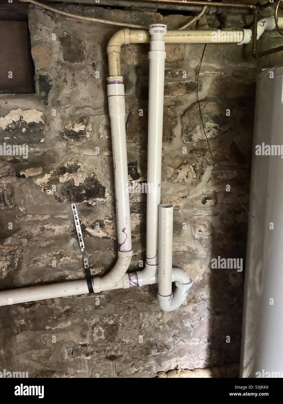 Drain Pipes Attached to an Old Stone Foundation Wall Stock Photo