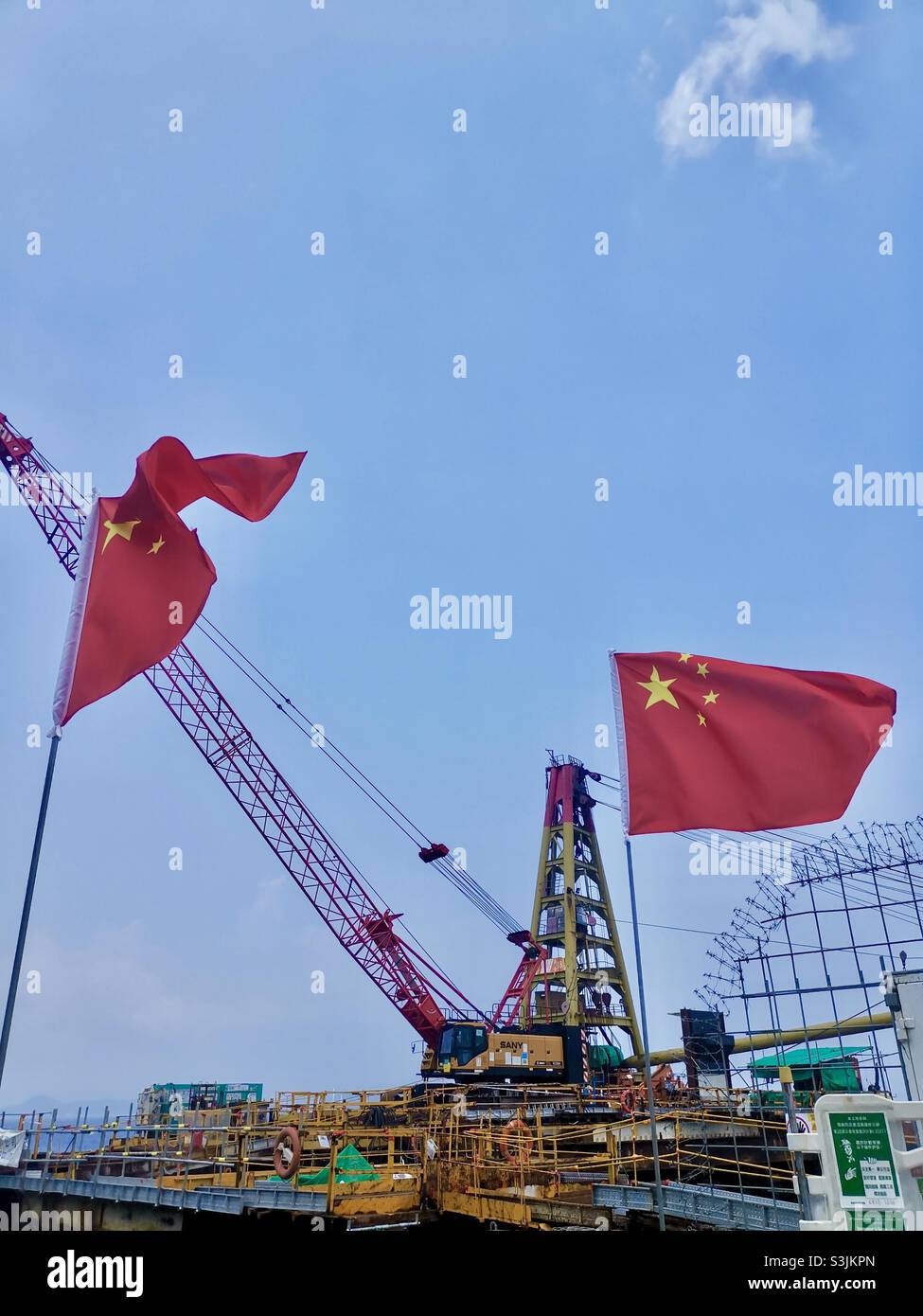 Chinese flags rising above the Pak Kok pier on Lamma island during the October 1st Chinese national day celebrations. - Smartphone Captured Stock Image
