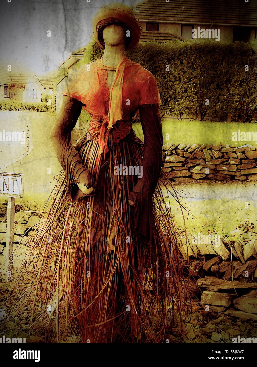 Artistic statue composed of straw standing by the roadside depicting a woman dressed in historic victorian costume - Smartphone Captured Stock Image