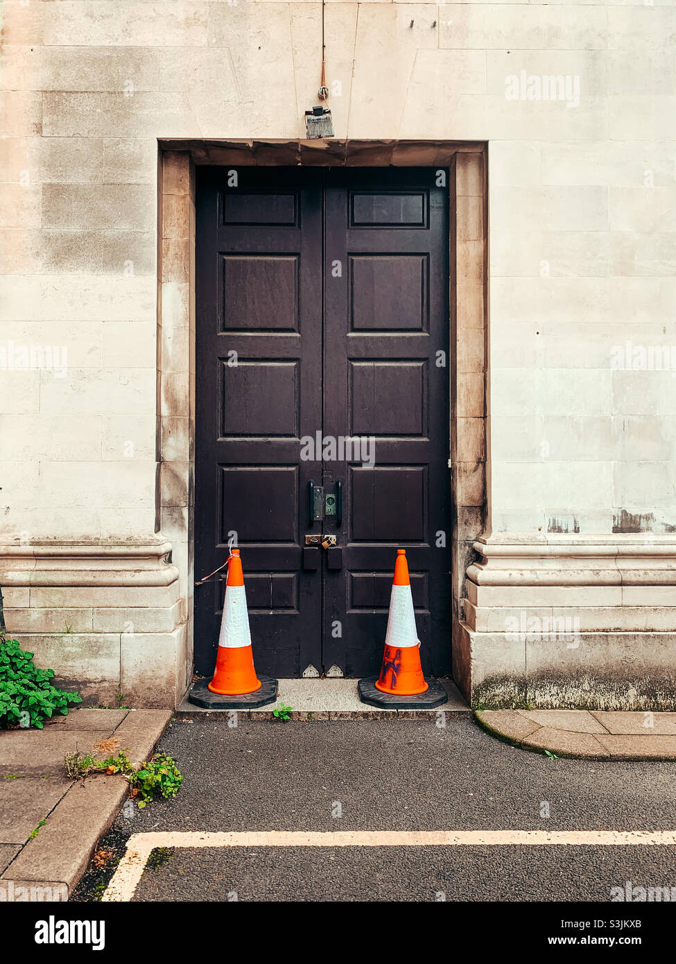 Closed double wooden doors with two traffic cones next to the doors - Smartphone Captured Stock Image