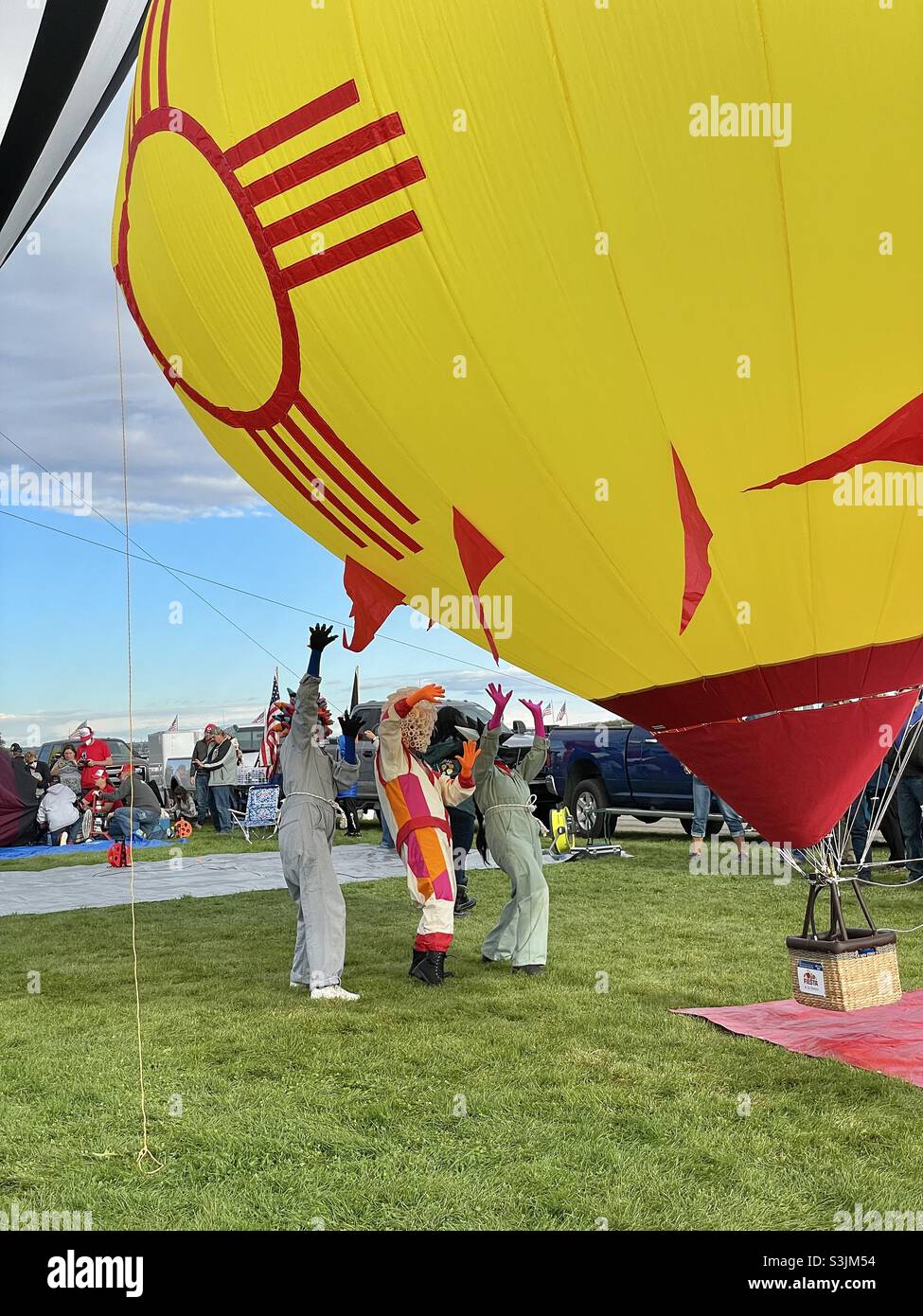 Three people dressed in costumes holding their arms up towards a yellow