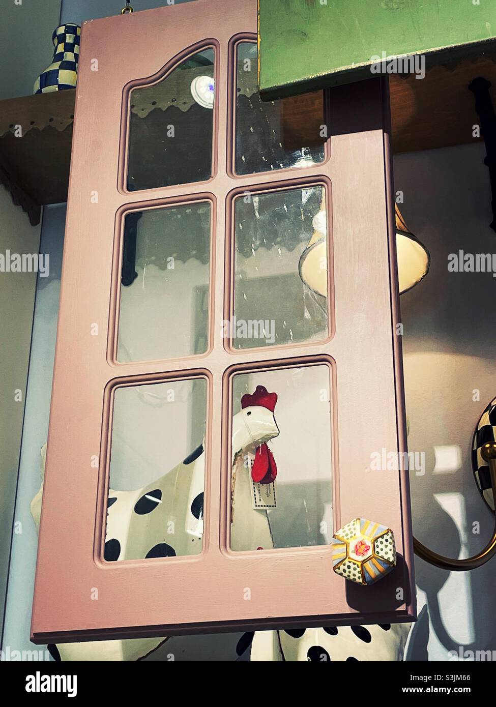 Humorous chicken statue looking through a stylized window pain at MacKenzie Childs, and accessory store in Soho, 2021, USA, NYCNYC - Smartphone Captured Stock Image