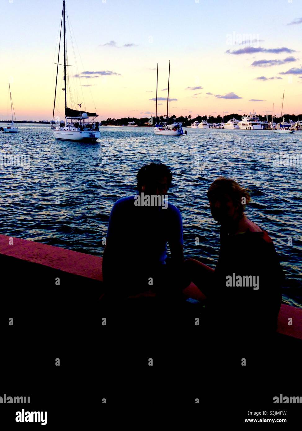 Silhouette of a romantic couple looking out of over the ocean in Miami Beach Florida - Smartphone Captured Stock Image