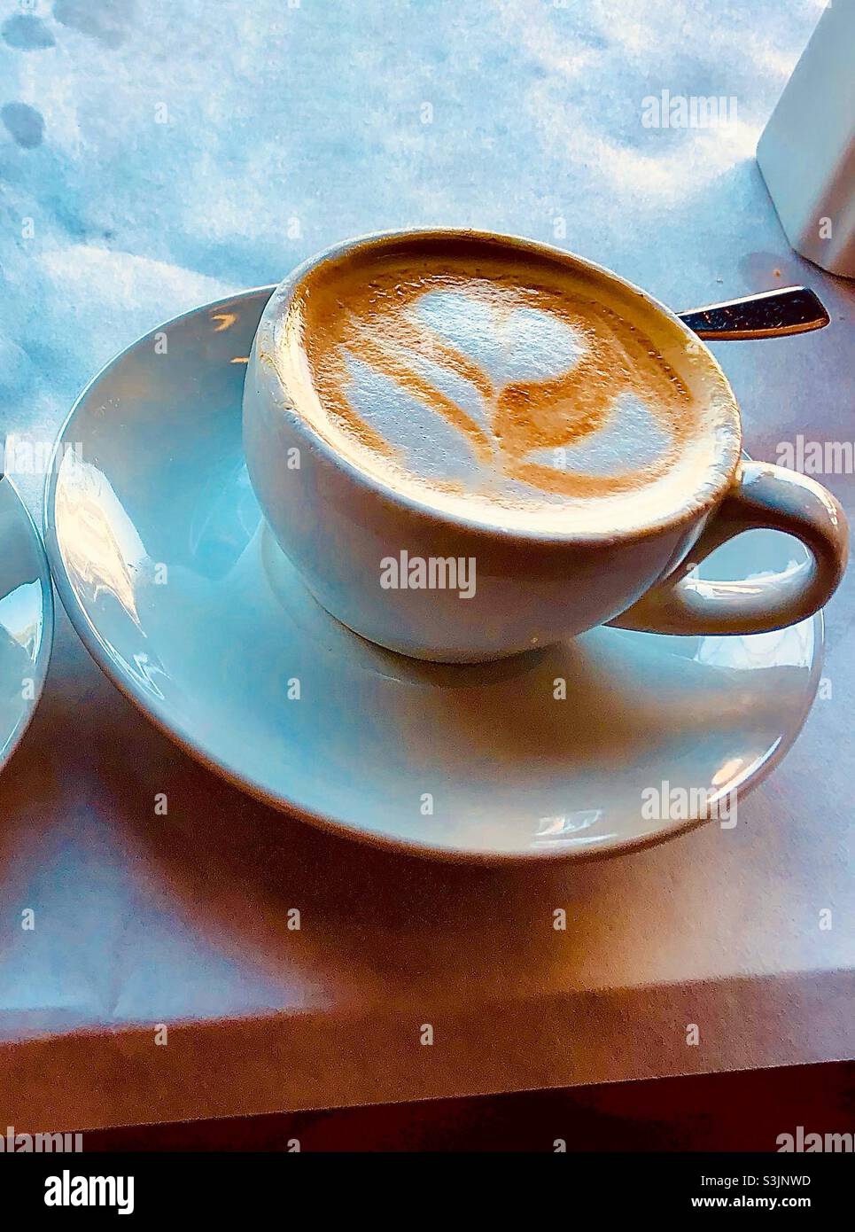 A cup of coffee with a flower design in the milkfoam - Smartphone Captured Stock Image