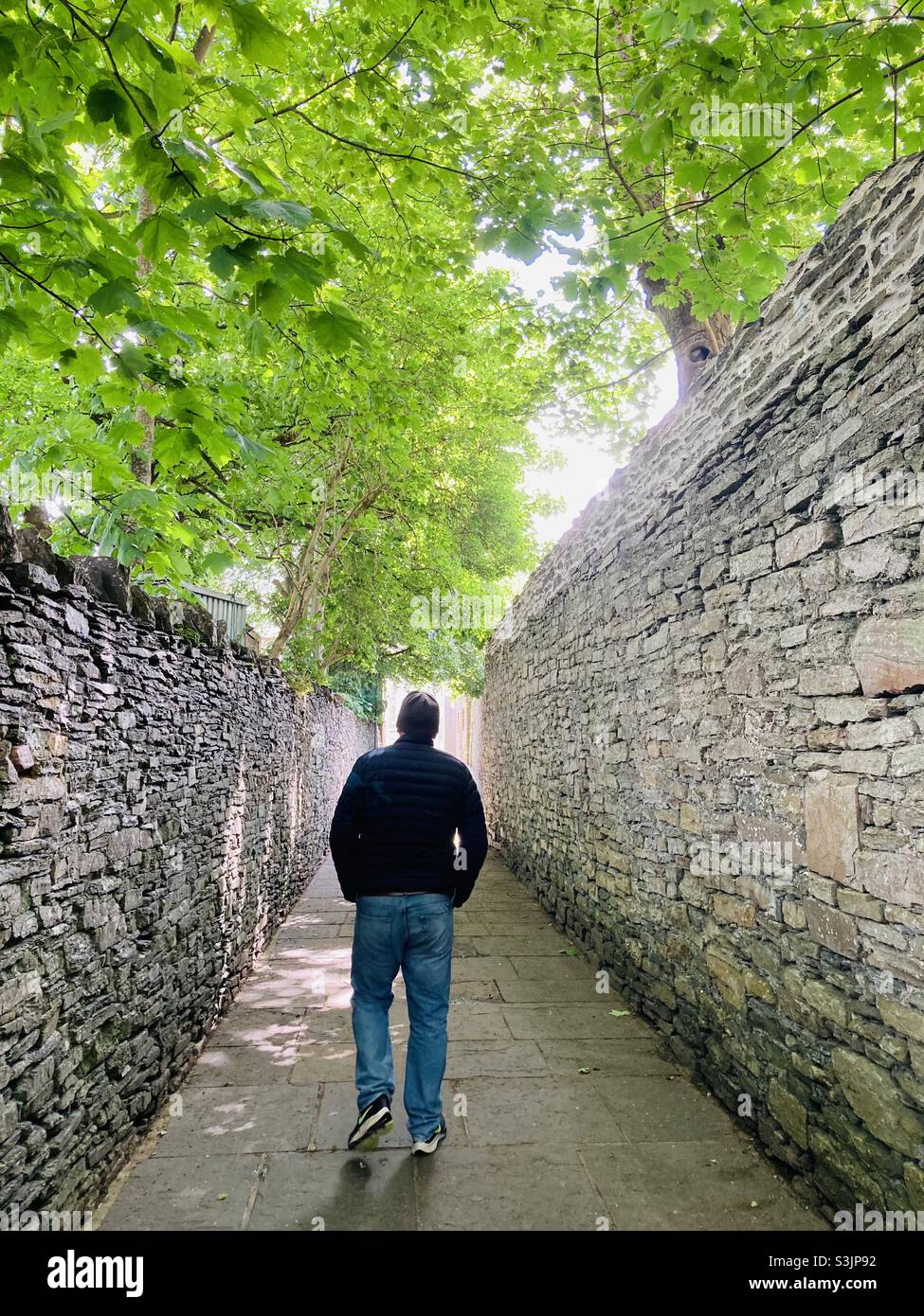 Man walking down a walled alley in Kirkwall Orkney Stock Photo