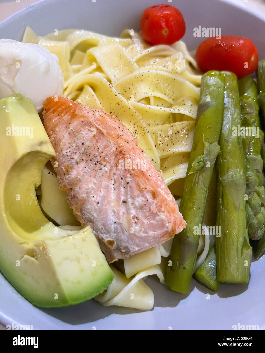 Ready to eat pasta with salmon, poached egg, asparagus tomatoes and avocado - Smartphone Captured Stock Image