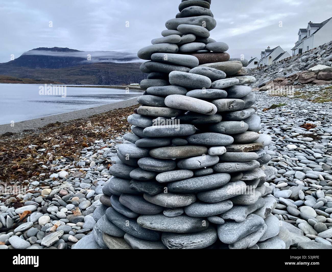 Cairn built on a Scottish beach, with mountains in the distance. - Smartphone Captured Stock Image
