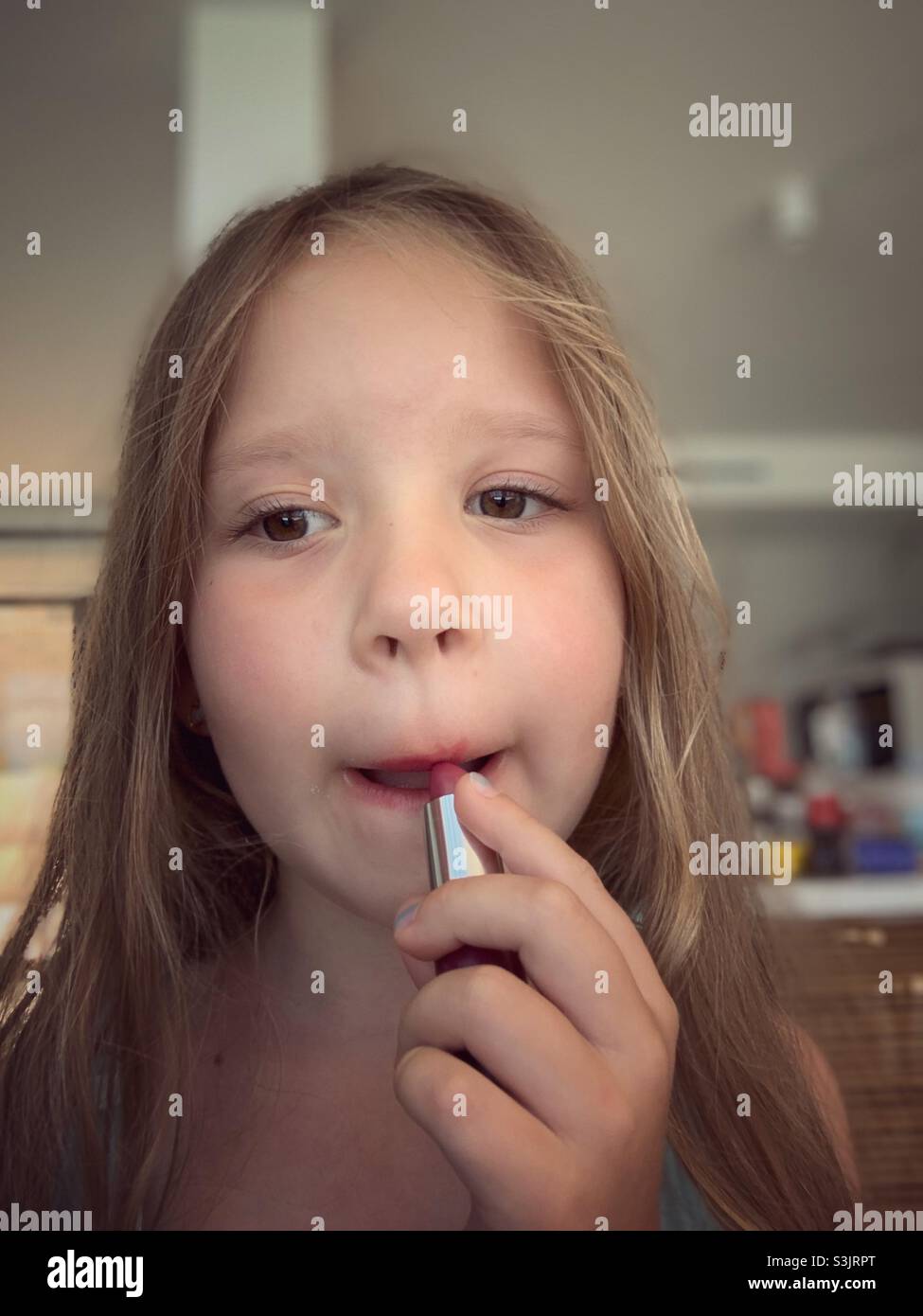 Cute little girl putting lipstick on Stock Photo Alamy
