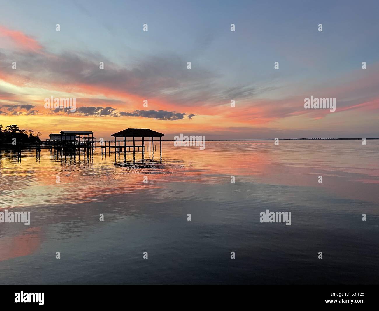 Dramatic colorful sunset skies setting over calm bay water with ...