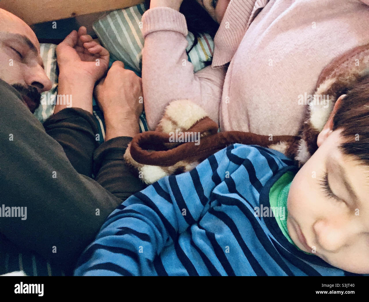 Close-up of tired family sleeping on bed, boy child, mother and father - Smartphone Captured Stock Image
