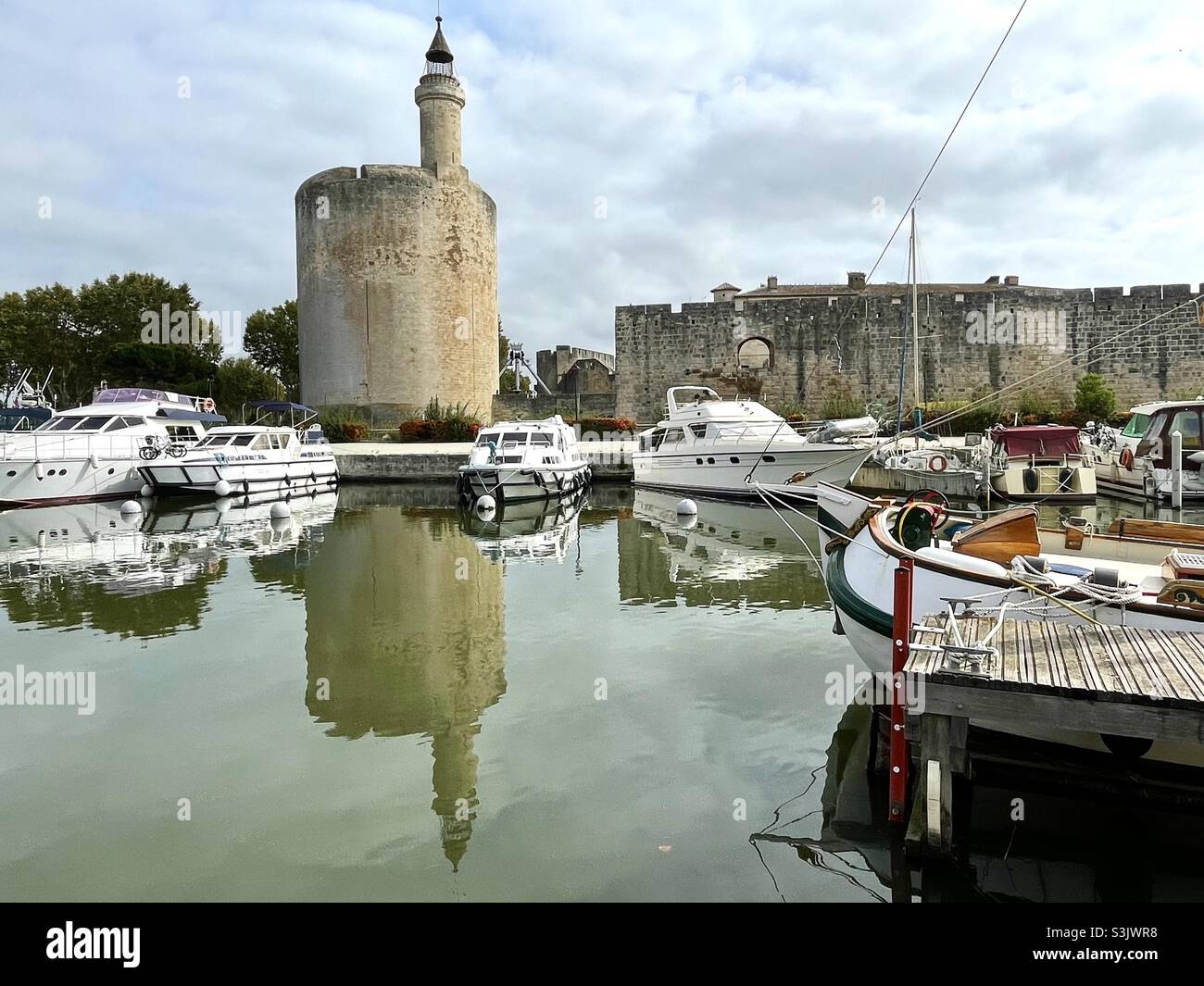 Aigues Mortes, Tower and citywall along canal with boats moored, Camargue, France Stock Photo