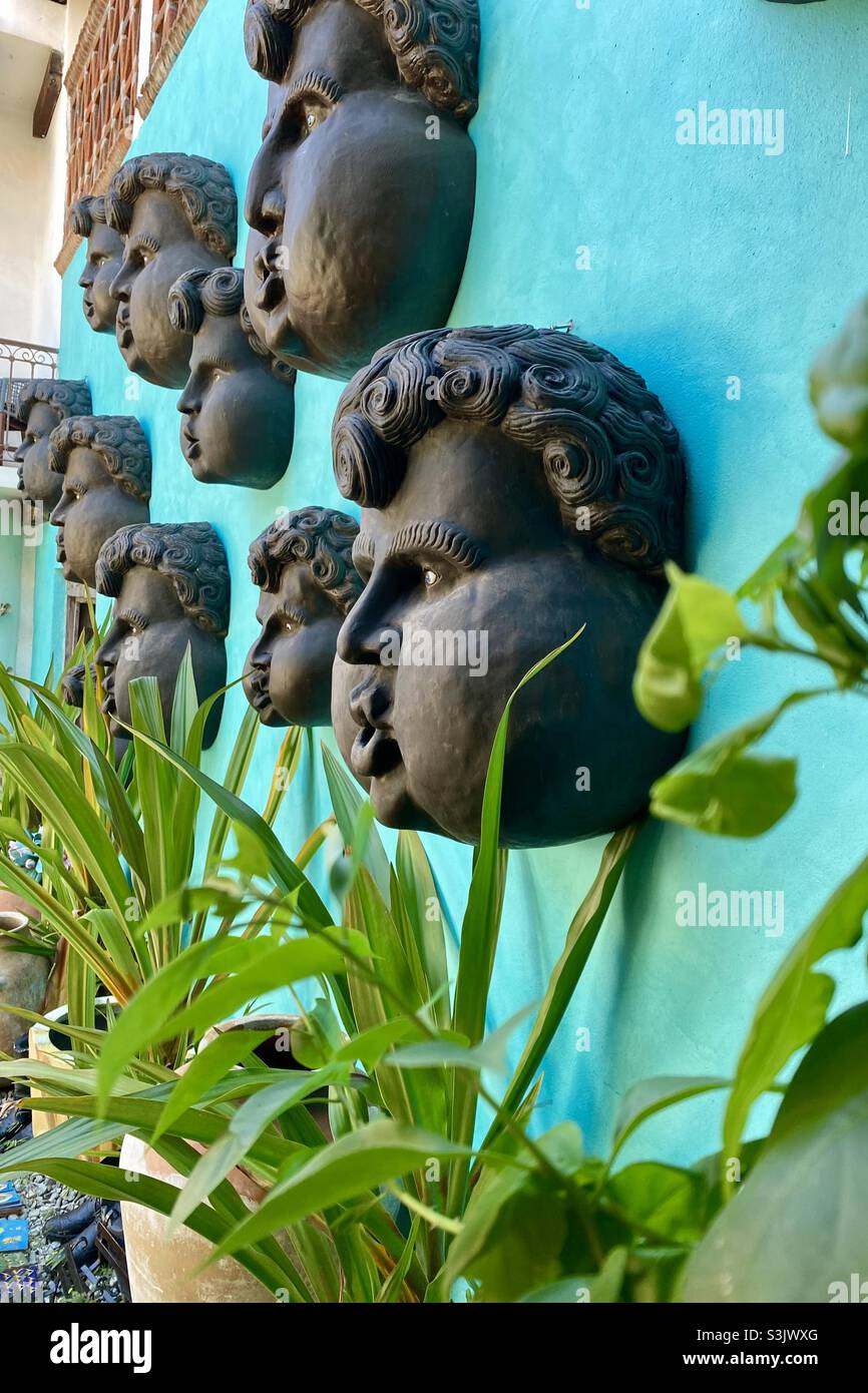 Outdoor scene in downtown Cabo with fountain heads on a turquoise wall Stock Photo