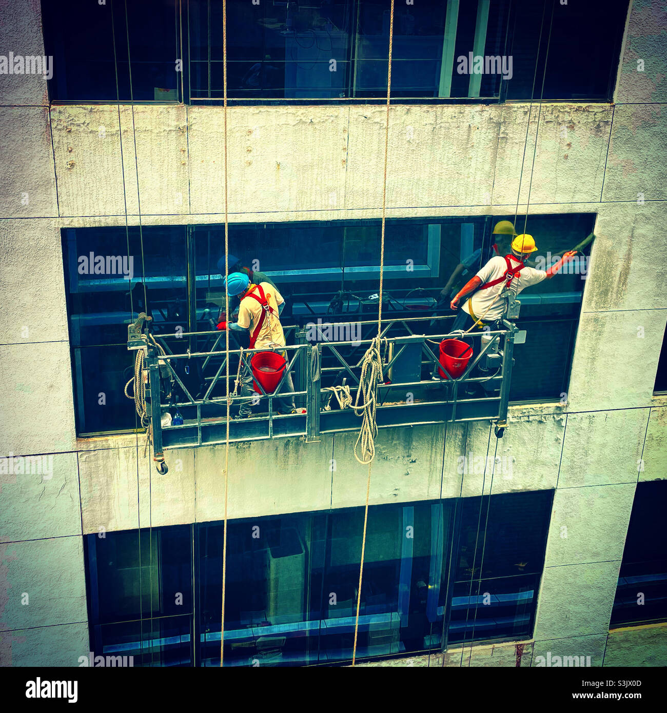 two men workers window cleaning a tower buillding in a financial district - Smartphone Captured Stock Image