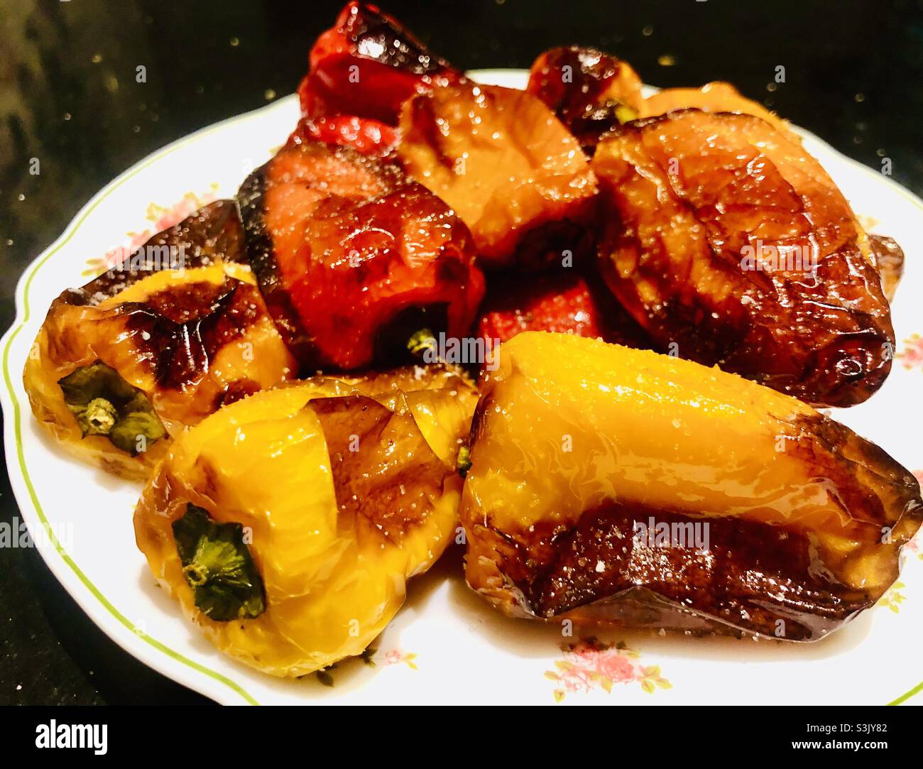 Red and yellow grilled peppers on white plate for dinner Stock Photo