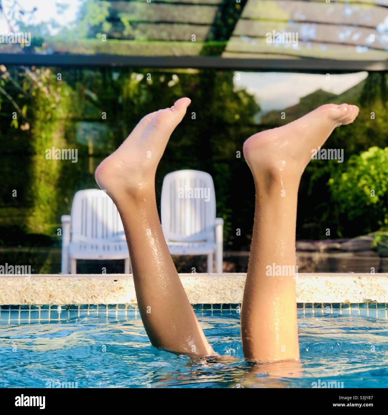 Upside down Caucasian girl’s legs in swimming pool Stock Photo