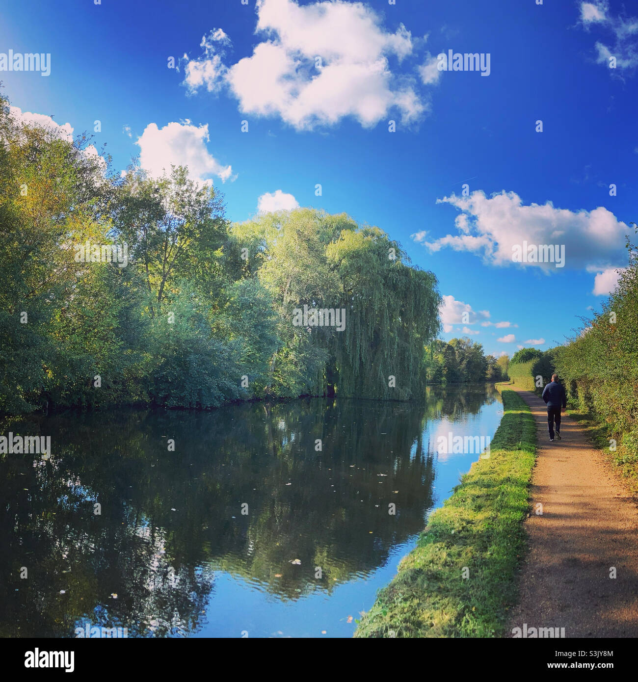 Reflections in the canal with man walking down the tow path in Cheshire - Smartphone Captured Stock Image