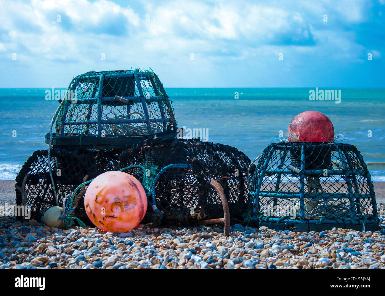 Lobster pots and bright orange buoys on the stony beach at St Leonard’s UK - Smartphone Captured Stock Image