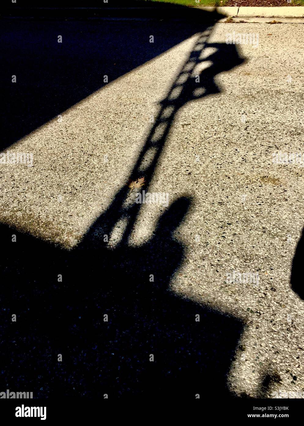 Climbing a tall ladder. One man holds the base while the other is near the top. As in a shadow play. Concepts: moving up, teamwork, iconic. Up down. Two is company. Stock Photo