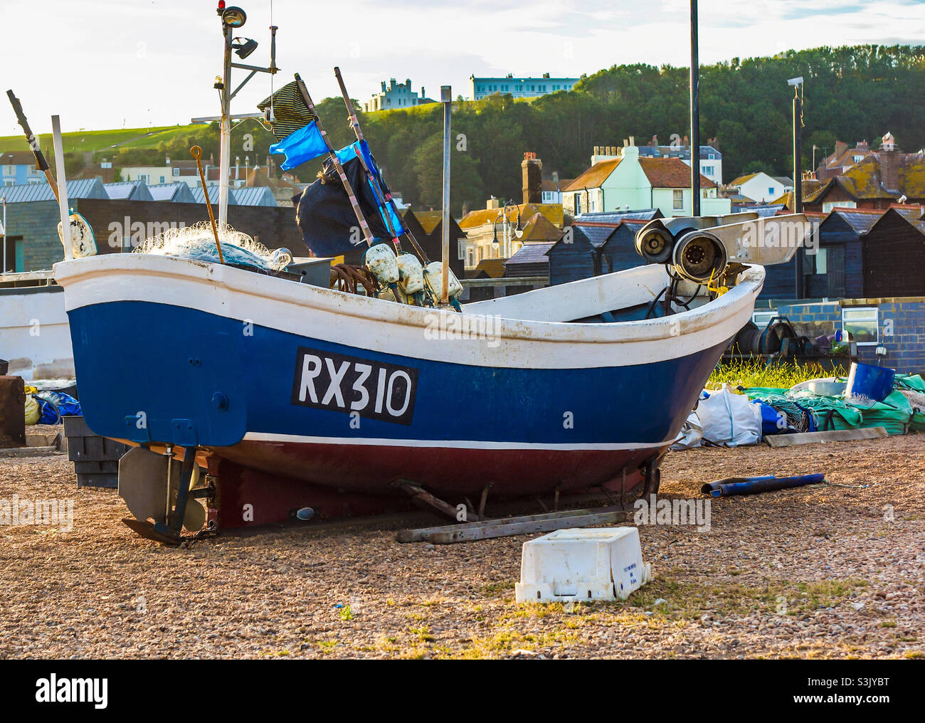 A fishing boat on a stony beach, a town can be  seen in the background - Smartphone Captured Stock Image