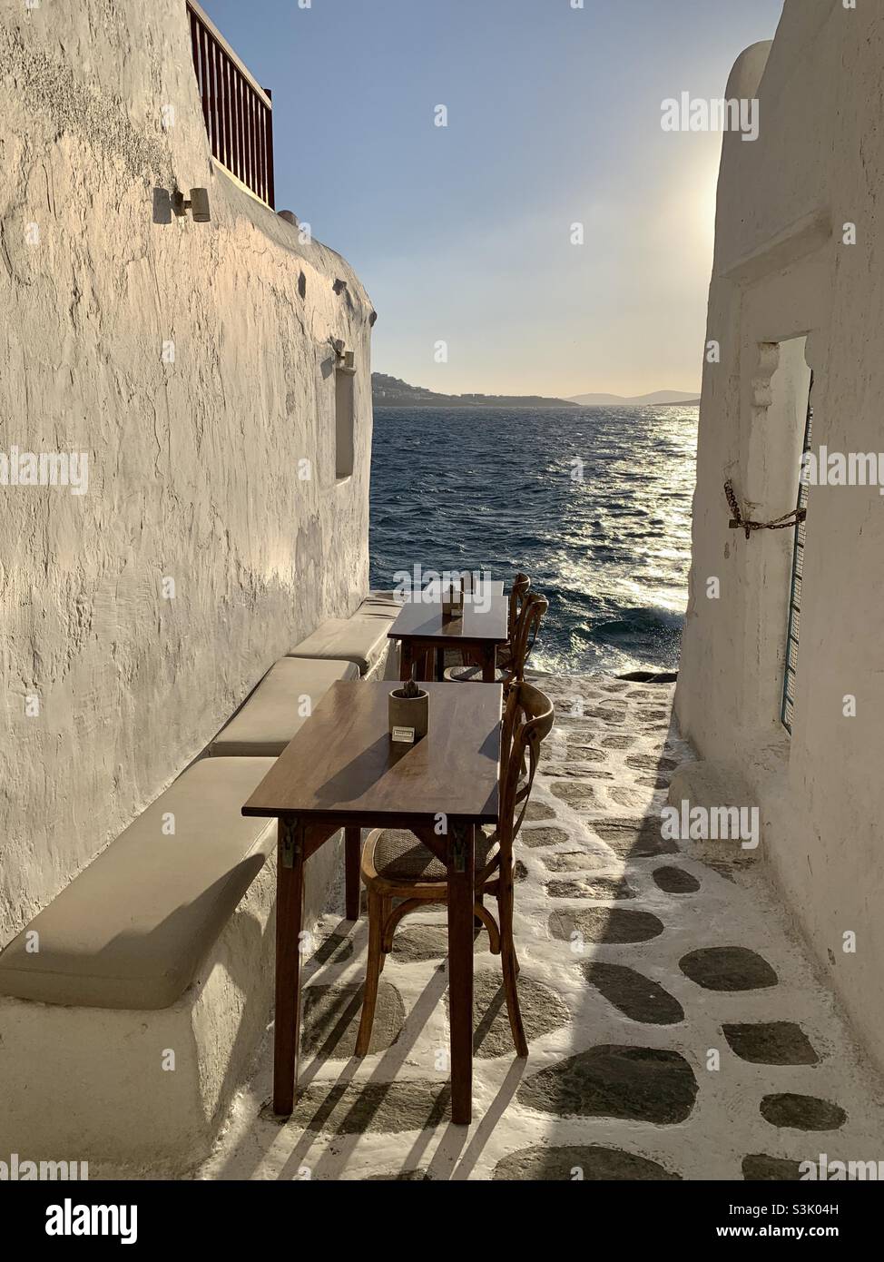 Tables and chairs looking out to the sea on Mykonos island at sunset Stock Photo