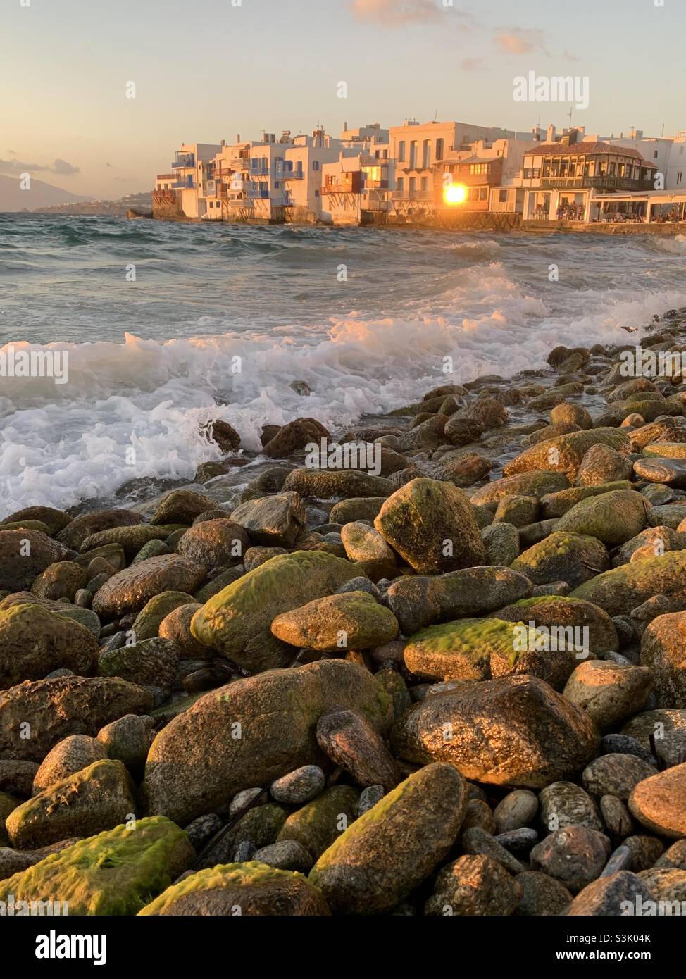 View from pebbly beach in Mykonos Greece at sunset Stock Photo